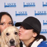 two alumni holding a golden retriever